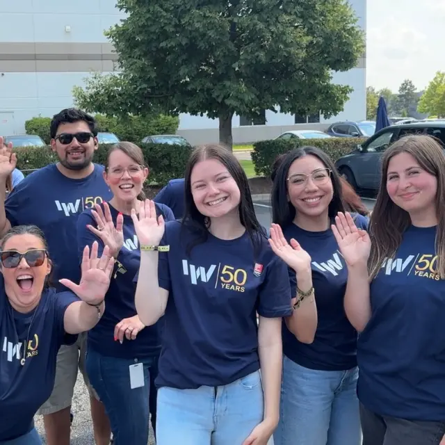 The Crew Behind Fifty Years at IW Technologies IW Technologies team members in 50 Years shirts wave together outside the Elgin facility.