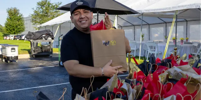 A Little Thank-You, Bagged Up from IW Technologies An IW Technologies team member smiles holding a 50 Years gift bag at a company event.